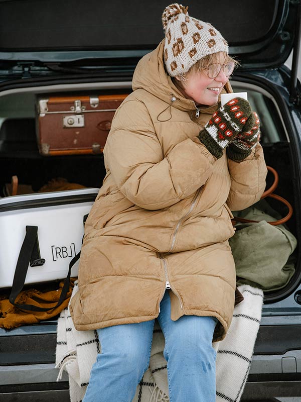 Frau mit Tasse von Rebel-Outdoor in Hand bei Auto